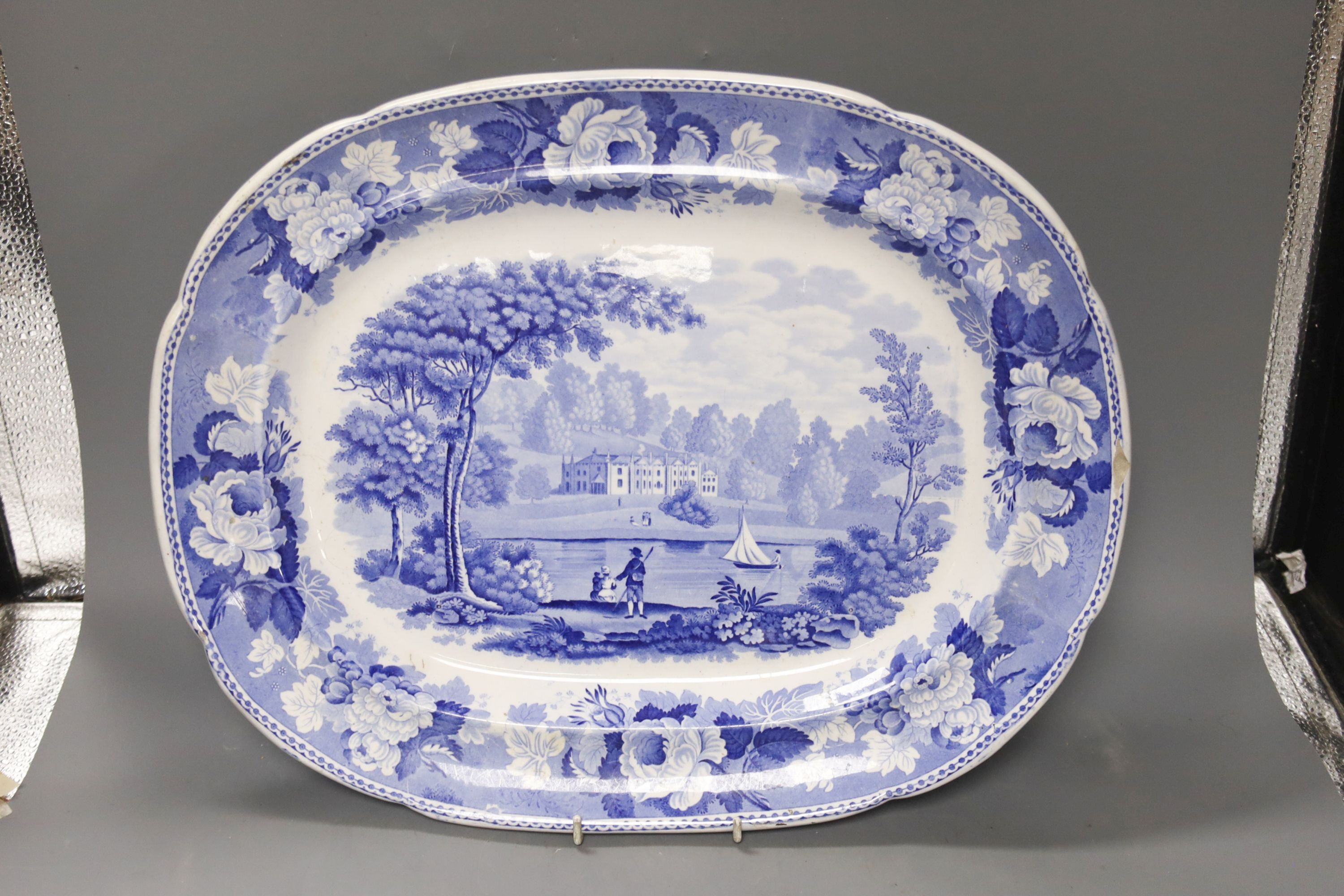 A late 19th century Staffordshire blue and white transfer-printed oval meat dish, ‘The Rokery’, depicting a country house with lake and figures, W 44cm and an octagonal 'Flora' creamware soup tureen with ladle and stand